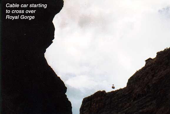 royalgorge-cablecar Ruth and I visited  Colorado's Royal Gorge, discovered by Zebulon Pike, and through which flows the Arkansas River, the most heavily rafted river in the United States, on business and pleasure in August, 2000 and took these photos.  Hope you enjoy them! Some facts about the highest Suspension Bridge at Royal Gorge Bridge and park, Canon City, CO:
• Construction on the world's highest suspension bridge began June 5, 1929, and completed Nov. 1929
• Length: 1,260 feet (384 meters)
• Width: 18 feet (5 meters)
• Main Span: 880 feet (268 meters)
• Towers: 150 feet high (46 meters)
• 2,100 strands of No. 9 galvanized wire
• Weight of cables: 300 tons
• 1,000 tons of steel in the floor of Bridge
• Walkway: made of 1,292 planks of deck; about 250 are replaced annually
• Original cost to build: $350,000 with a cost today of about $20 million
• Bridge will support in excess of two million pounds
• Listed on the National Historic Register

About the longest single-span Aerial Tram
• Built in 1968 at a cost of $350,000
• Length: 2,200 feet (671 meters)
• Height above Arkansas River: 1,178 feet (359 meters)
• Power: direct current motor
• Auxiliary gasoline emergency standby engine
• Maximum speed: 11.4 mph
• Capacity of cabin: 35 passengers
• Track cables weigh over seven tons each
• More than two miles of cables utilized in tramway system
• Safety: wind-warning gauges working at all times; tram will not operate during severe weather or gusty winds


About the world's steepest Incline Railway
• Construction began in 1930 and completed in 1931
• Length of incline: 1,550 feet (473 meters)
• 100% grade, 45-degree angle
• Powered by Otis Elevator with a completely automatic SCR drive system
• Standby emergency diesel engine
• Maximum speed: 11.4 mph
• Rate of descent: 3 mph
• Weight of cars: 4,500 lbs.
• Travel time: 5.5 minutes each way
• Same engineering and construction crews that built the Bridge
• Safety: 19 manually operated stopping devices, also equipped with automatic governor to stop each car
• Listed on the National Historic Register