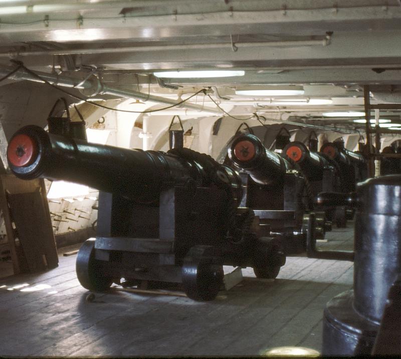 16-gun_deck Gun deck.  The piping for fire sprinklers and the florescent lamps are modern touches, of course.  In the old days, this deck would have been painted red to hide the blood being shed preventing panic among the crew.