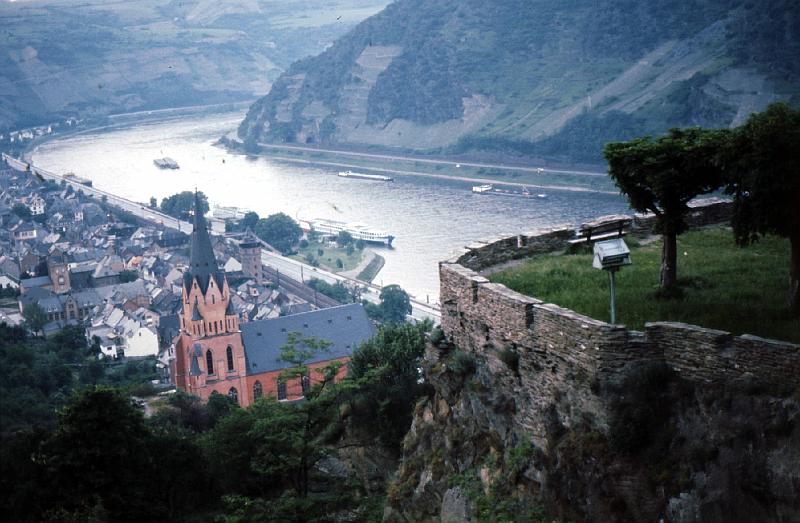 Loreli_from_Marksburg Loreli Rock from Marksburg Castle. [From Web sites]: The mighty slate rock Lorelei in the Romantic Rhine Valley - around 16 miles/ 25 km from Rudesheim and 50 miles/80 km from Frankfurt airport - rises up almost vertically to 145 yards/132m above the water-level. Downstream the river is squeezed into its narrowest and deepest (24 yards/22m) point, so the Middle Rhine at this point used to be very difficult to navigate and the correct passage is (today) clearly marked with buoys.

Even in the 19th century, reefs and rapids made it extremely dangerous for ships to pass this point. The legend tells us, that a siren called 